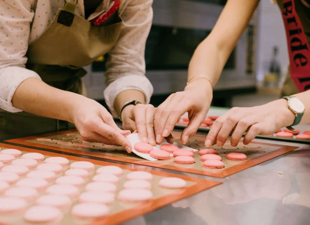 Participants préparant des macarons roses en atelier pâtisserie