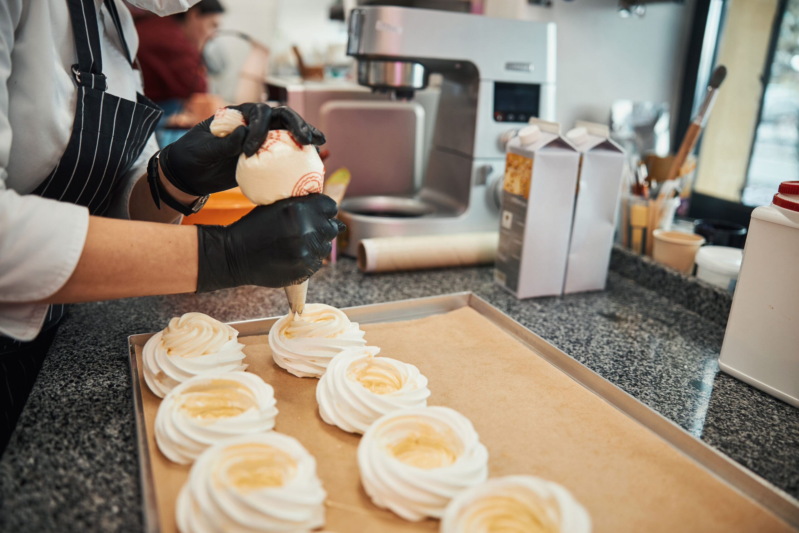 Pâtissière garnissant des meringues en atelier